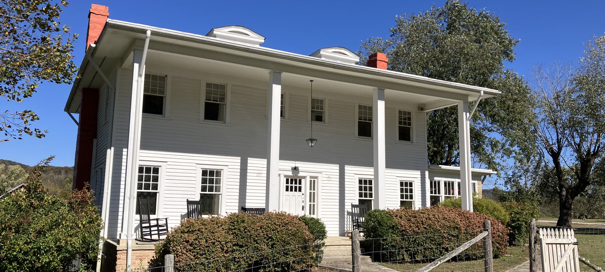 two story white house with four thin pillars in front of it for stability
