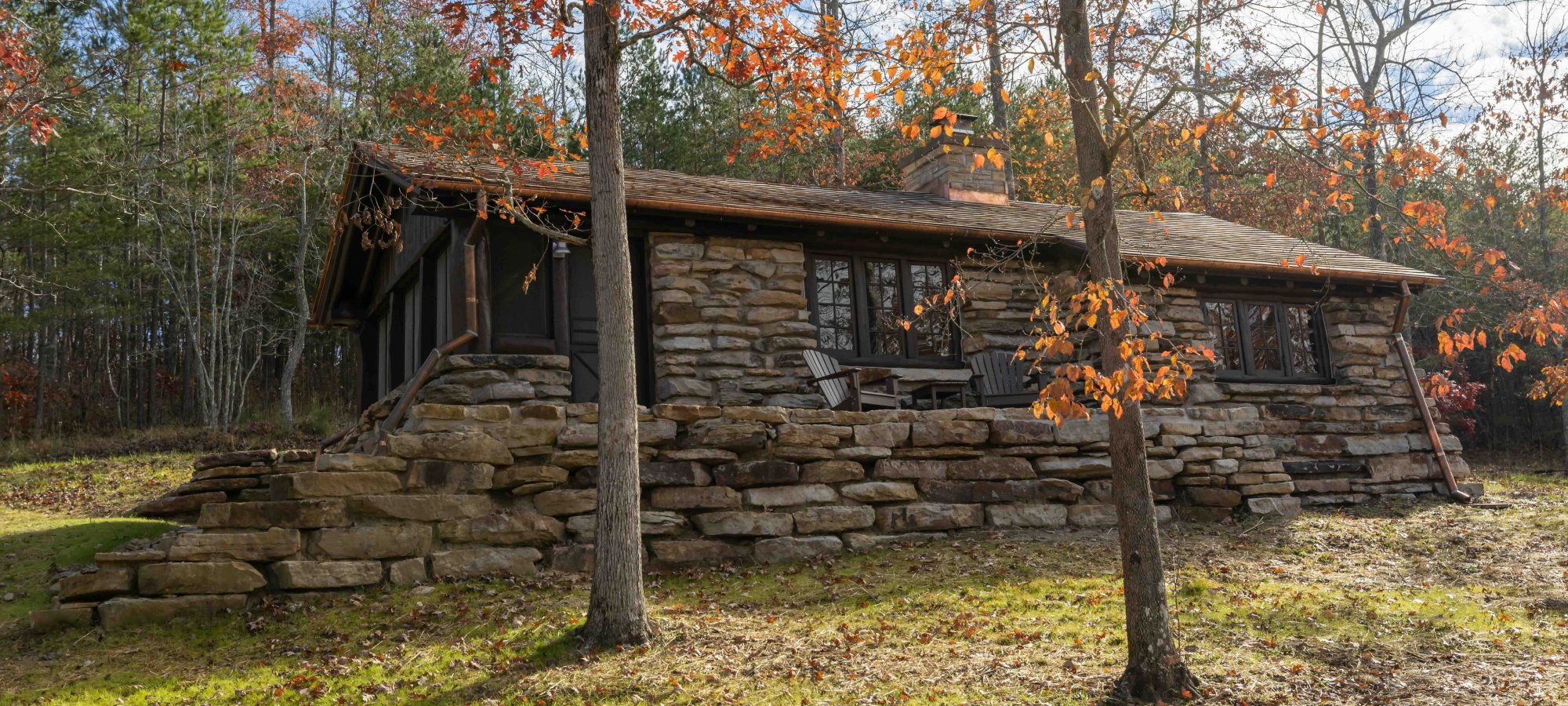 Stone cabin in a forest surrounded by trees in the fall