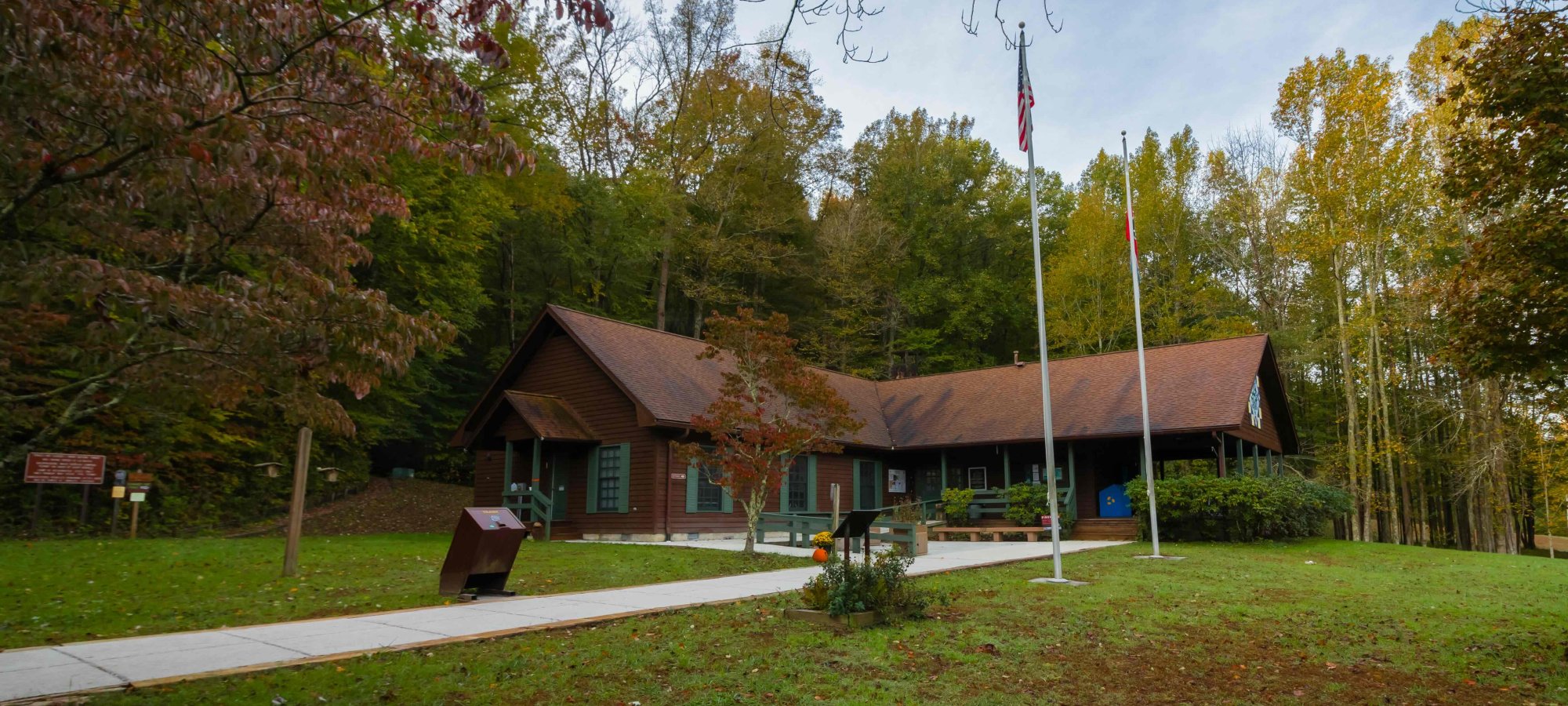 Rustic cabin in a forest setting with flagpole and clear path.