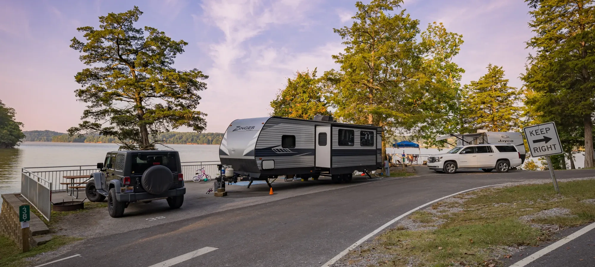RVs parked by a serene lake during sunset.