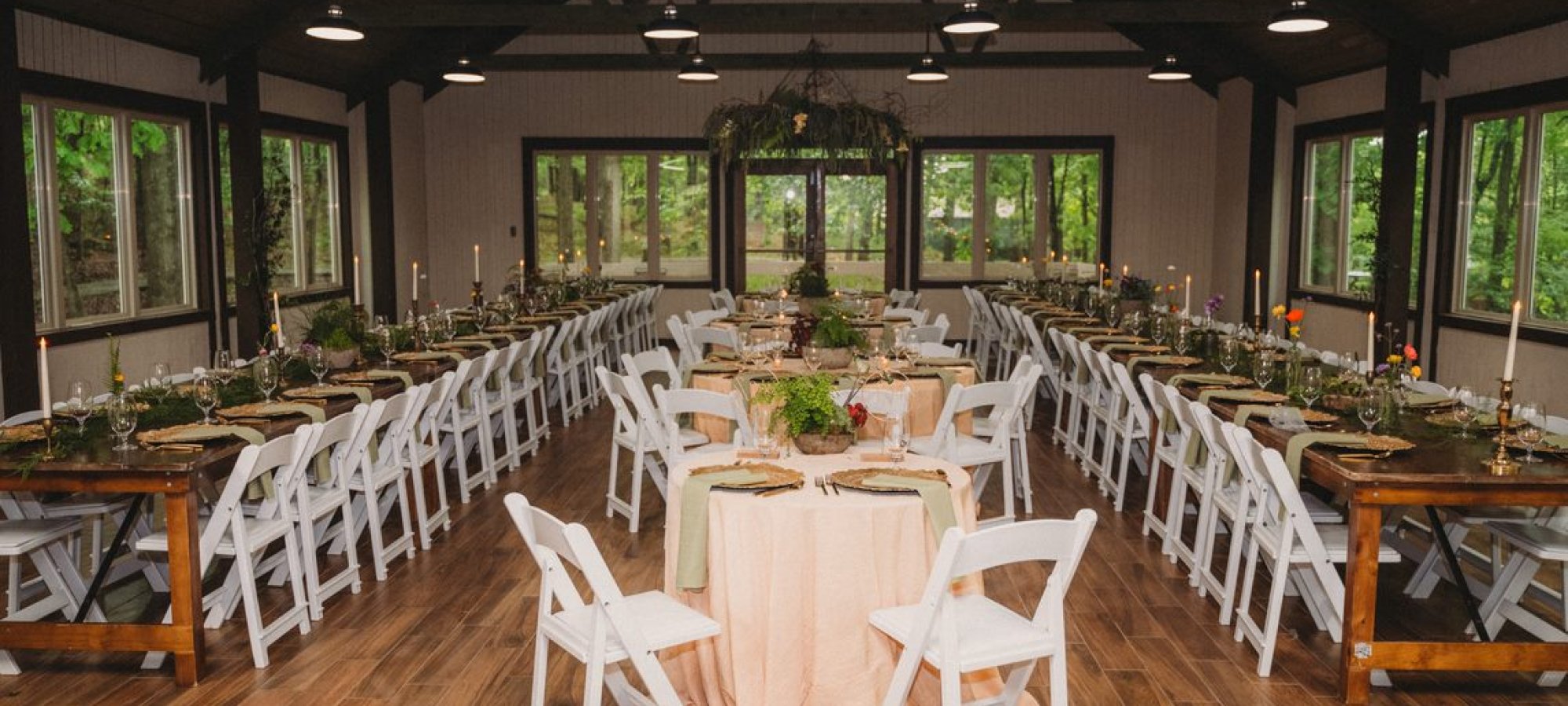Elegant wedding venue with tables, white chairs, and green centerpieces.