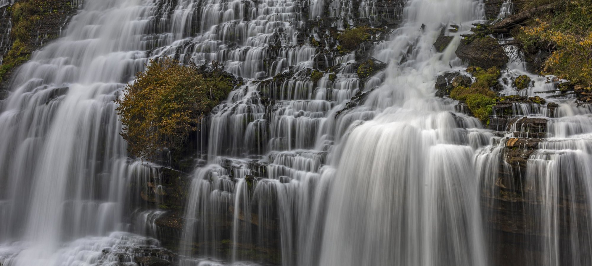 Cascading waterfall over moss-covered cliffs.