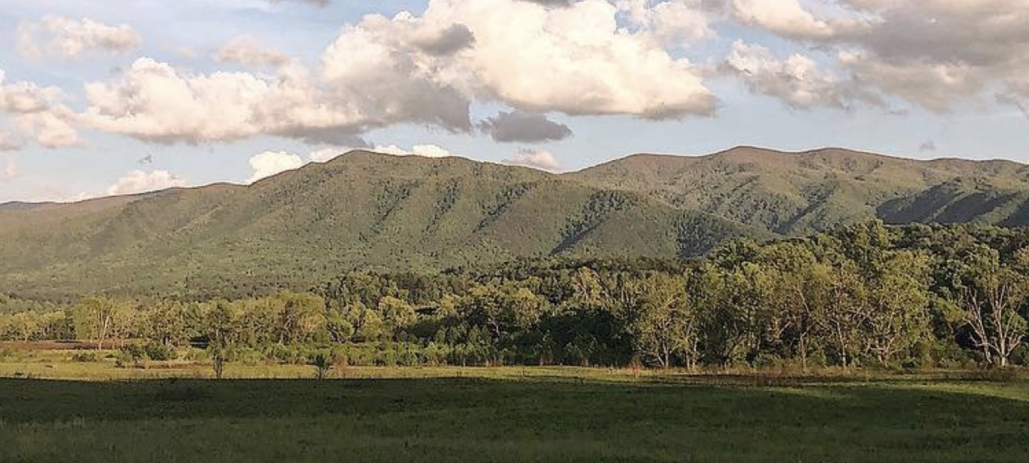 Mountainous landscape with green hills under a cloudy sky.