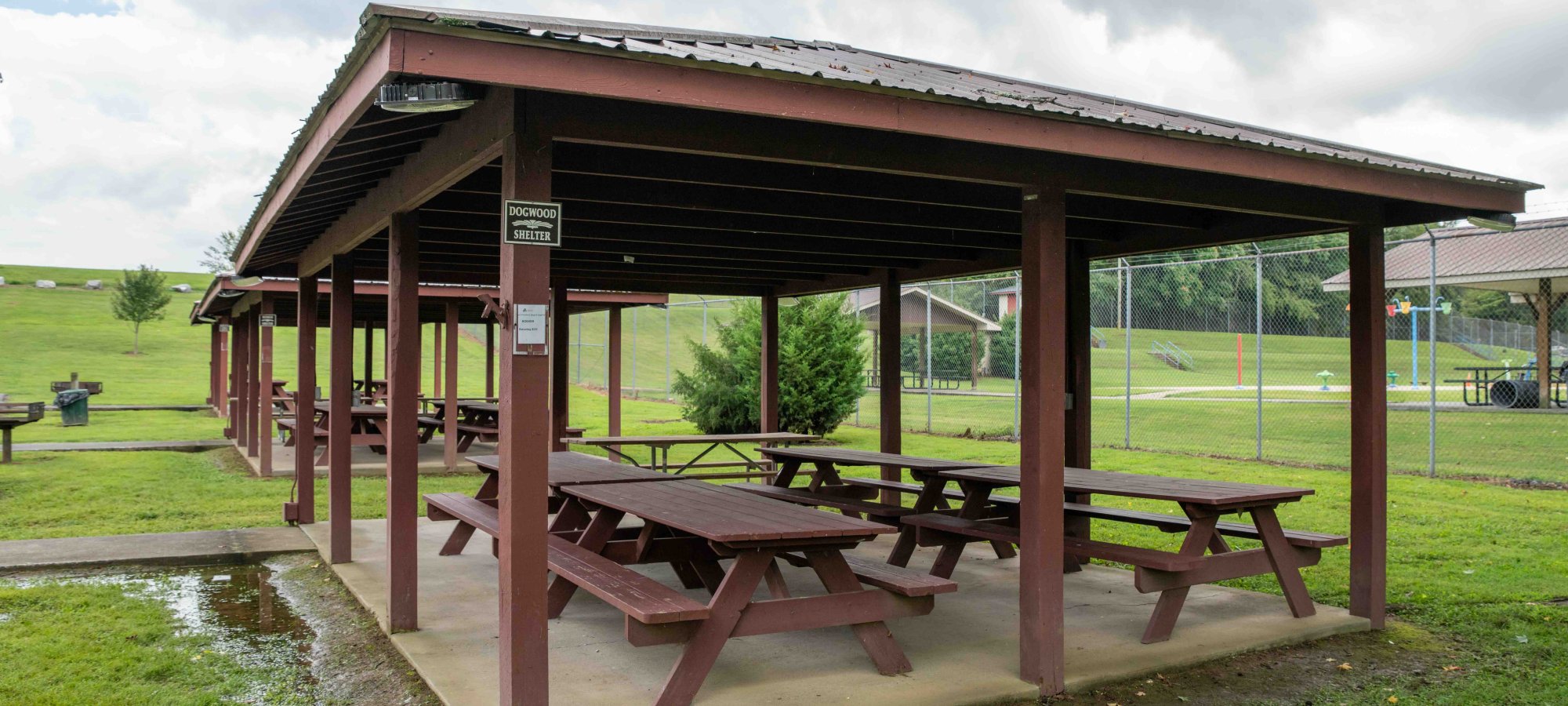 a row of shelters that offer picnic tables and have a concrete path leading to them.