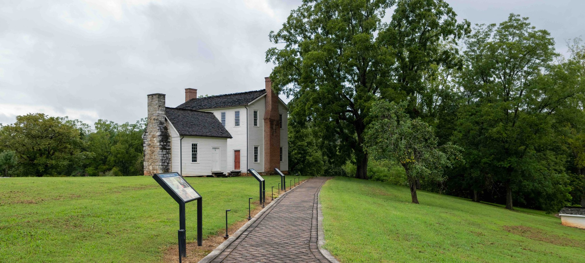concrete trail that leads towards white house with several chimneys.