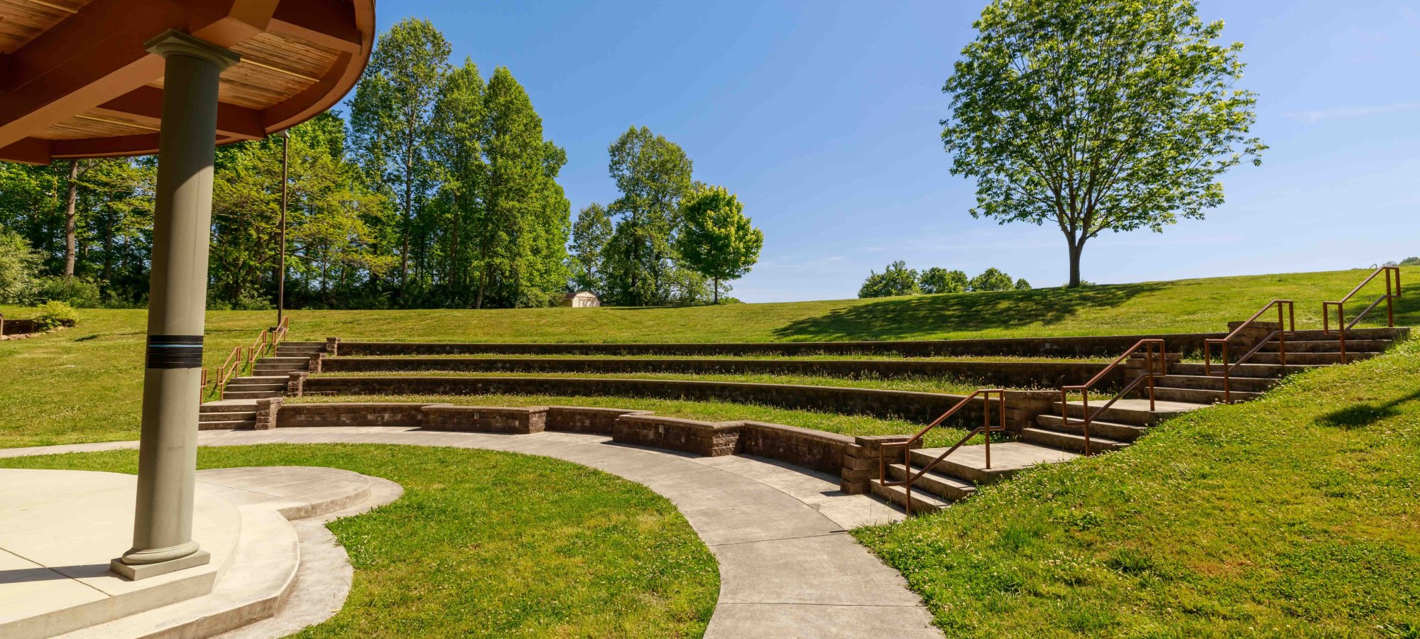 Amphitheater with a concrete path and grass and stone seating.