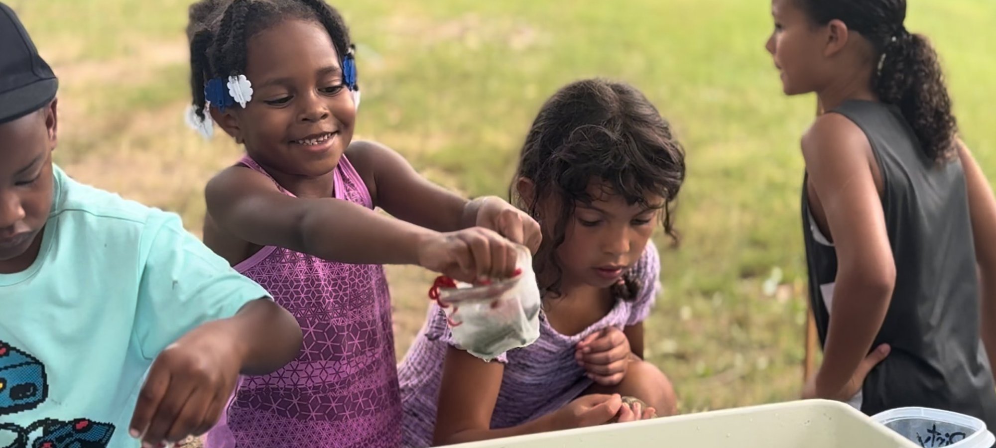 Children engaged in outdoor activity, playing with water and toys.