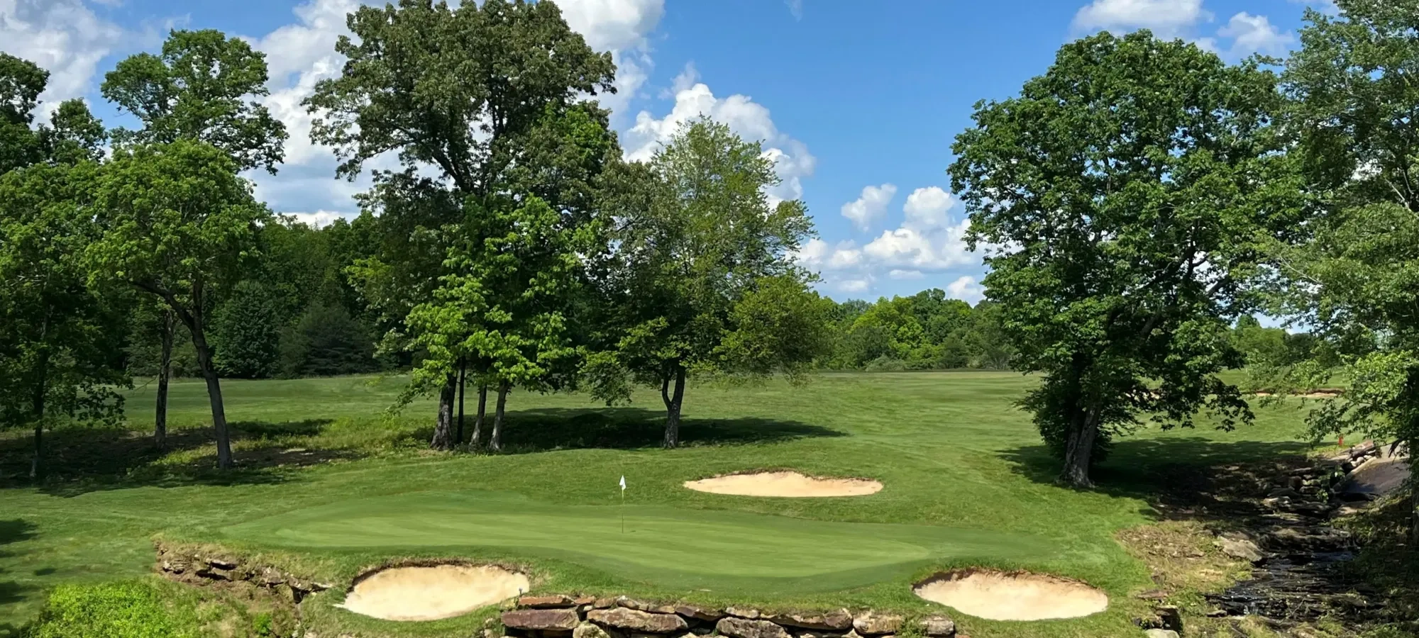 A golf course hole surrounded by sand traps and lush trees