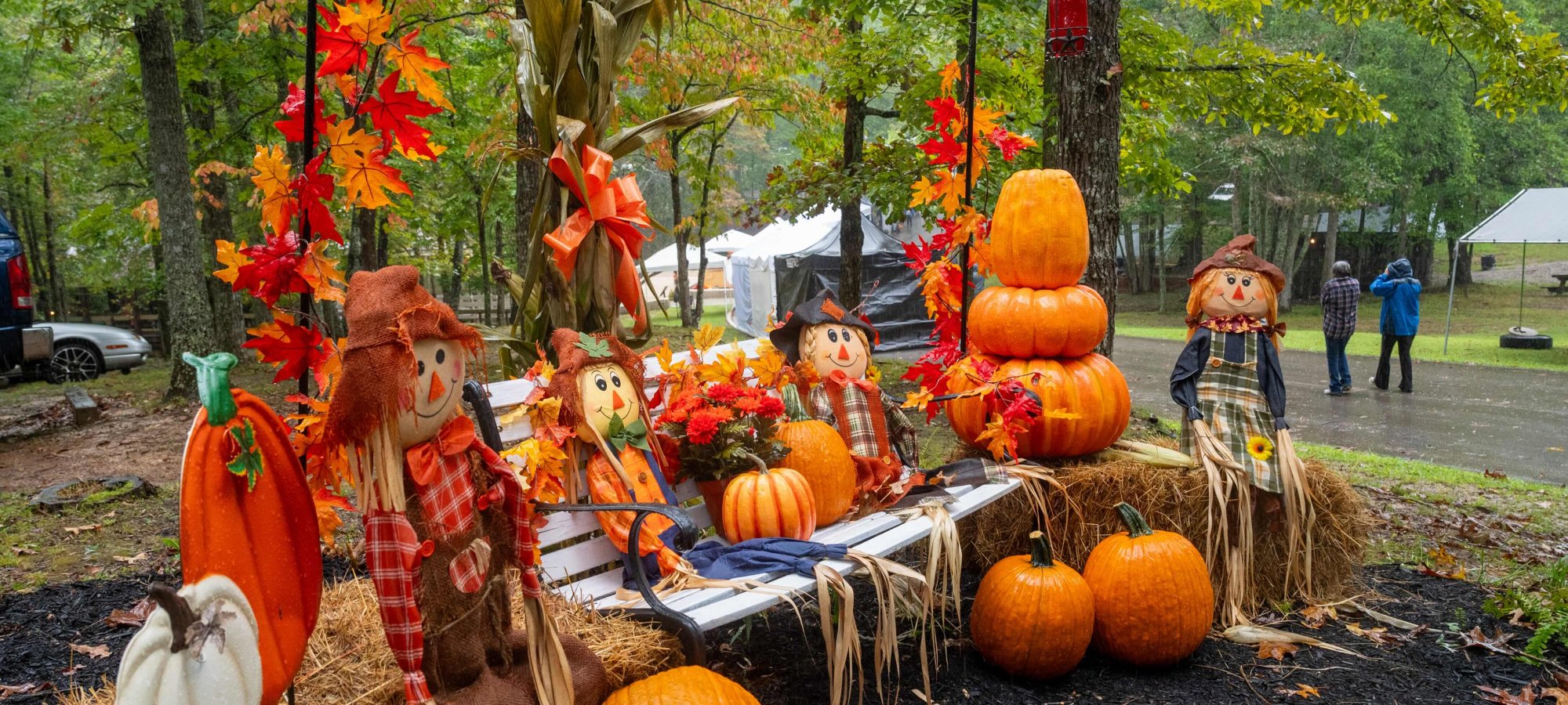 Autumn festival display with pumpkins, hay bales, and scarecrows outdoors.