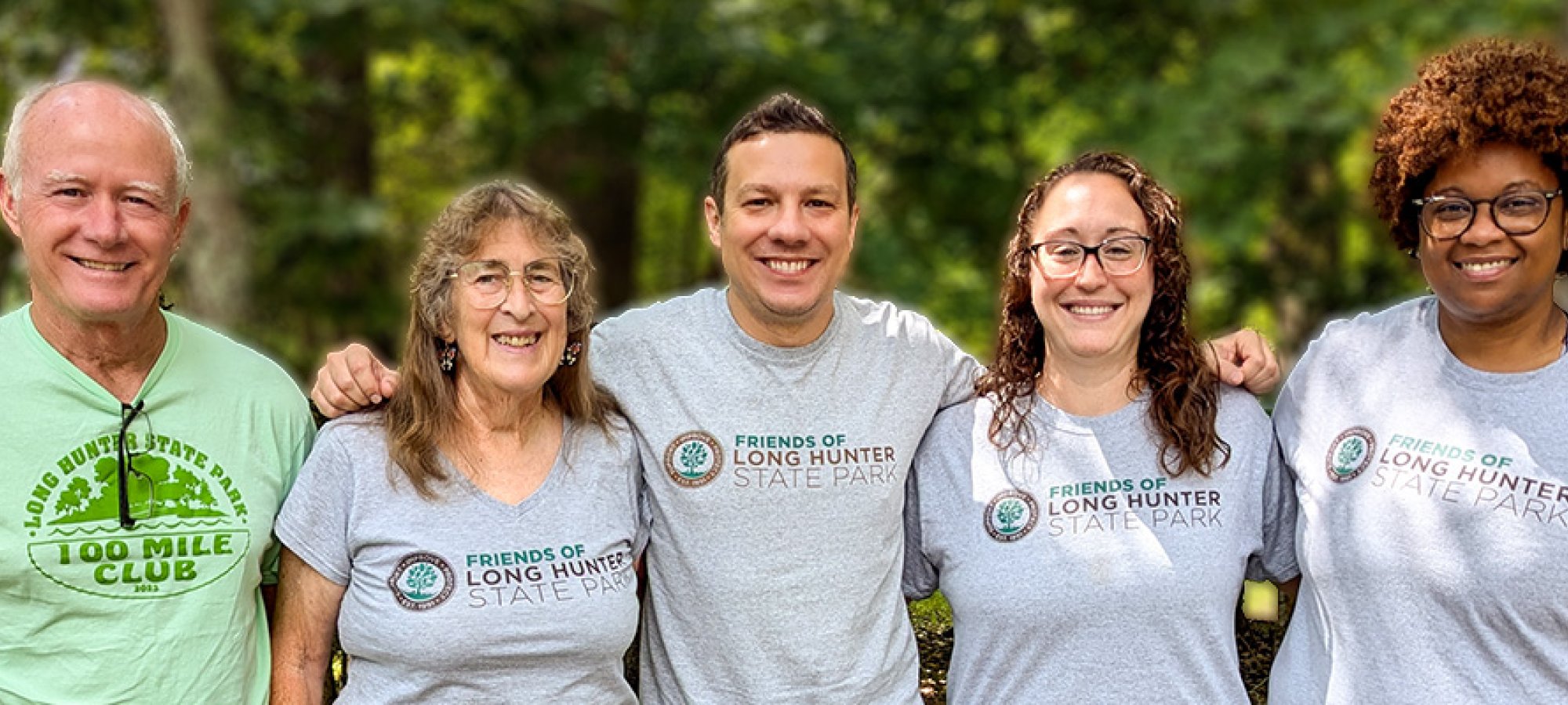 A group of five people wearing matching Friends of Long Hunter t-shirts stand together outside