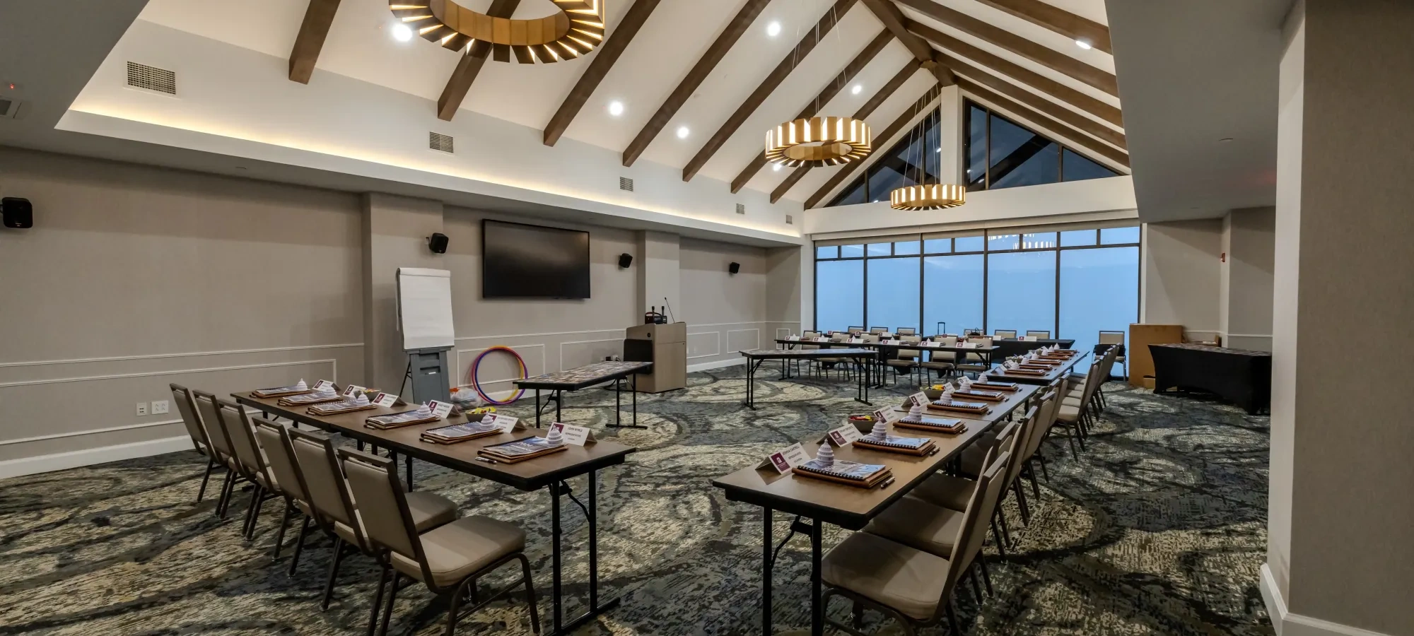 Modern conference room with seating arranged around tables facing a presentation screen.