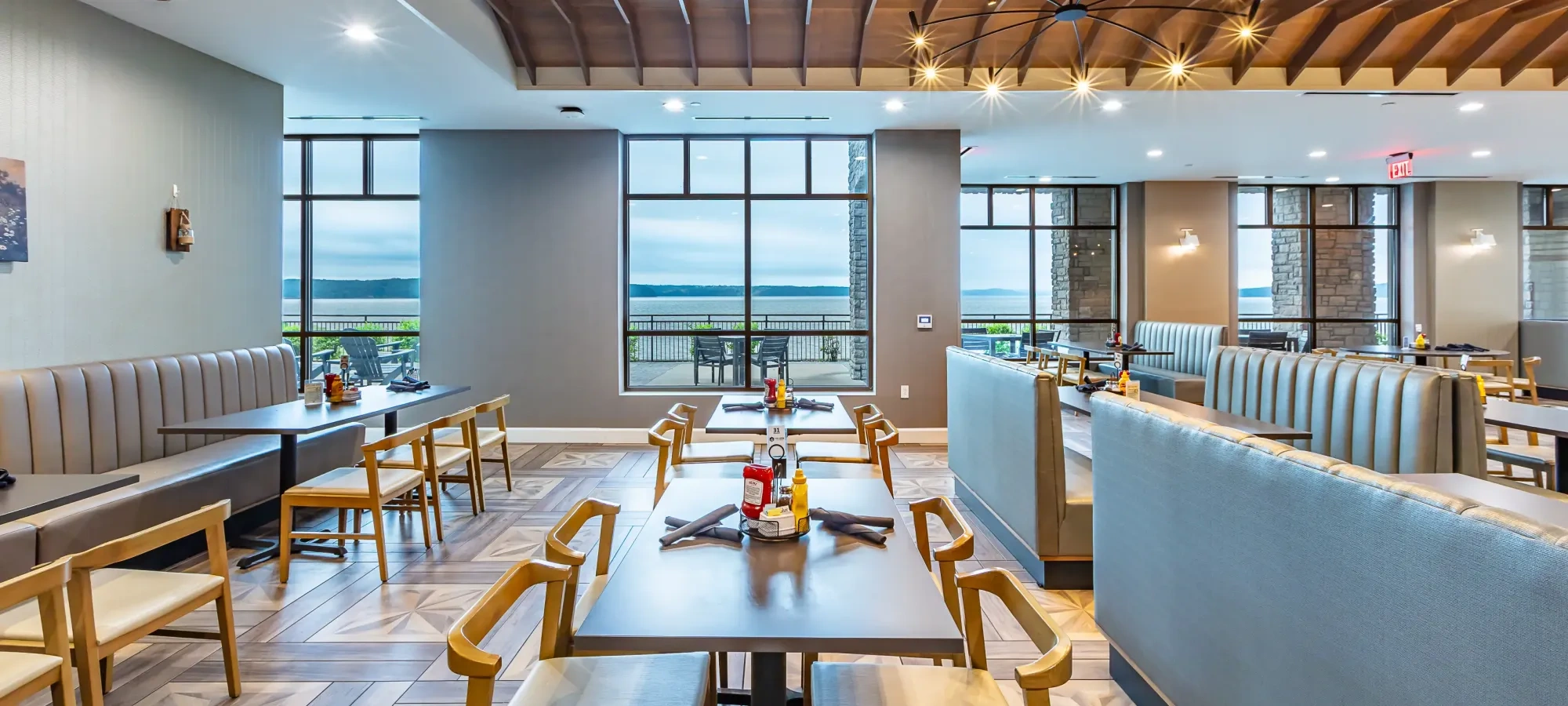 The interior of a restaurant with booths, tables and chairs looking out over a lake view