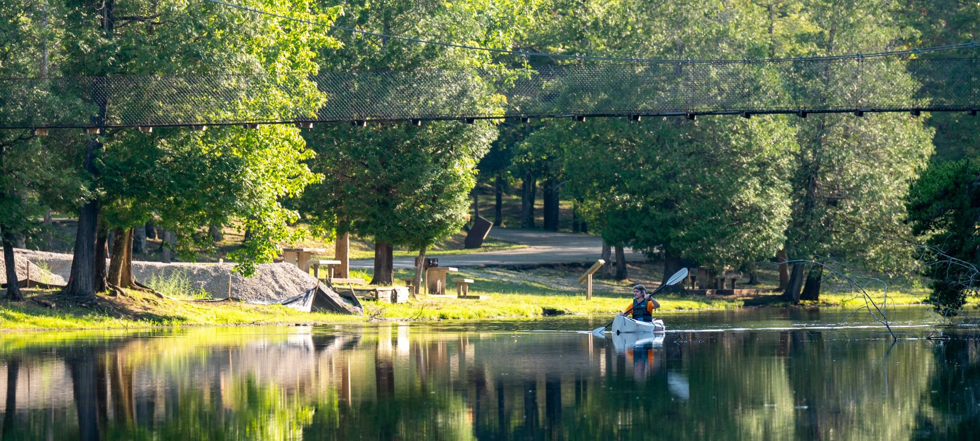 Serene lake scene with a boat, surrounded by lush green trees.