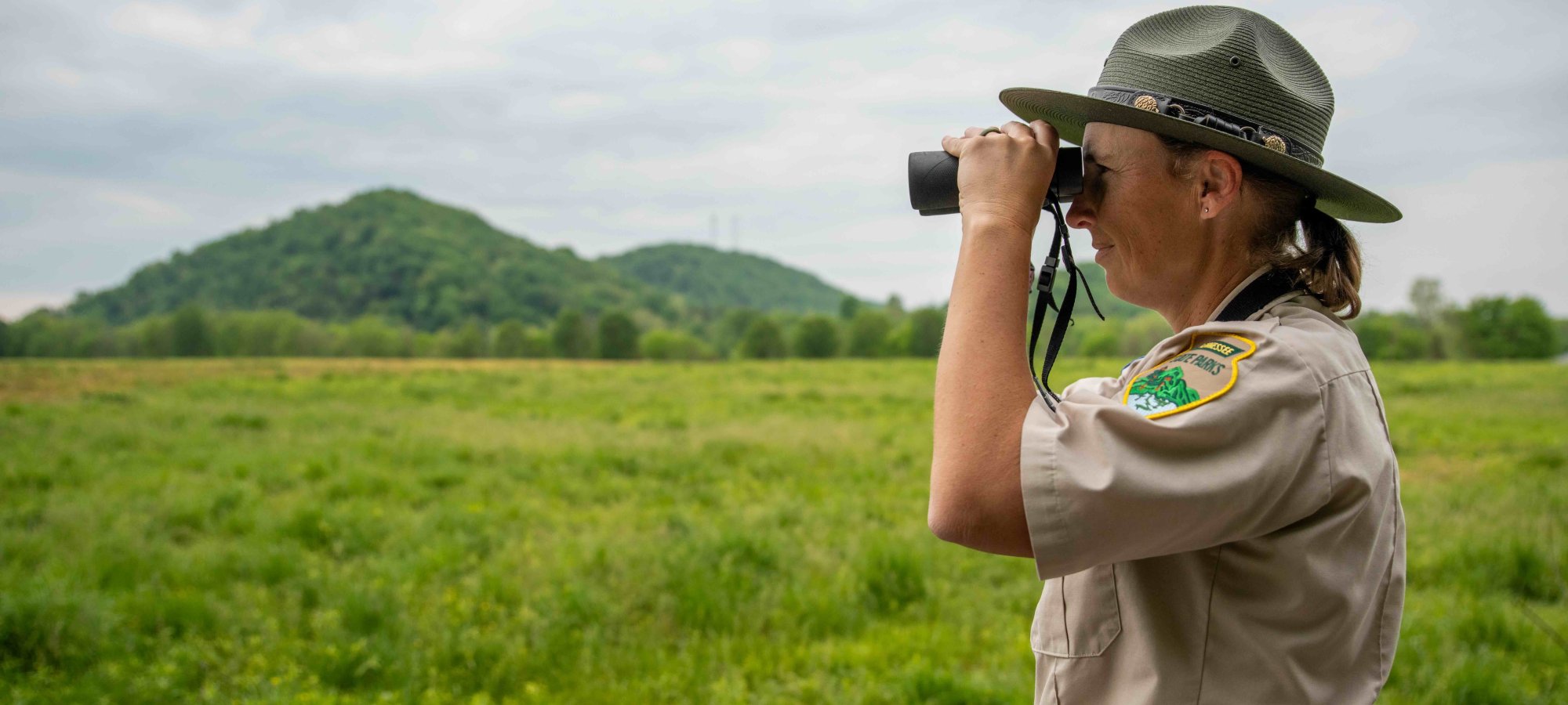 girl ranger with binoculars looking in a field