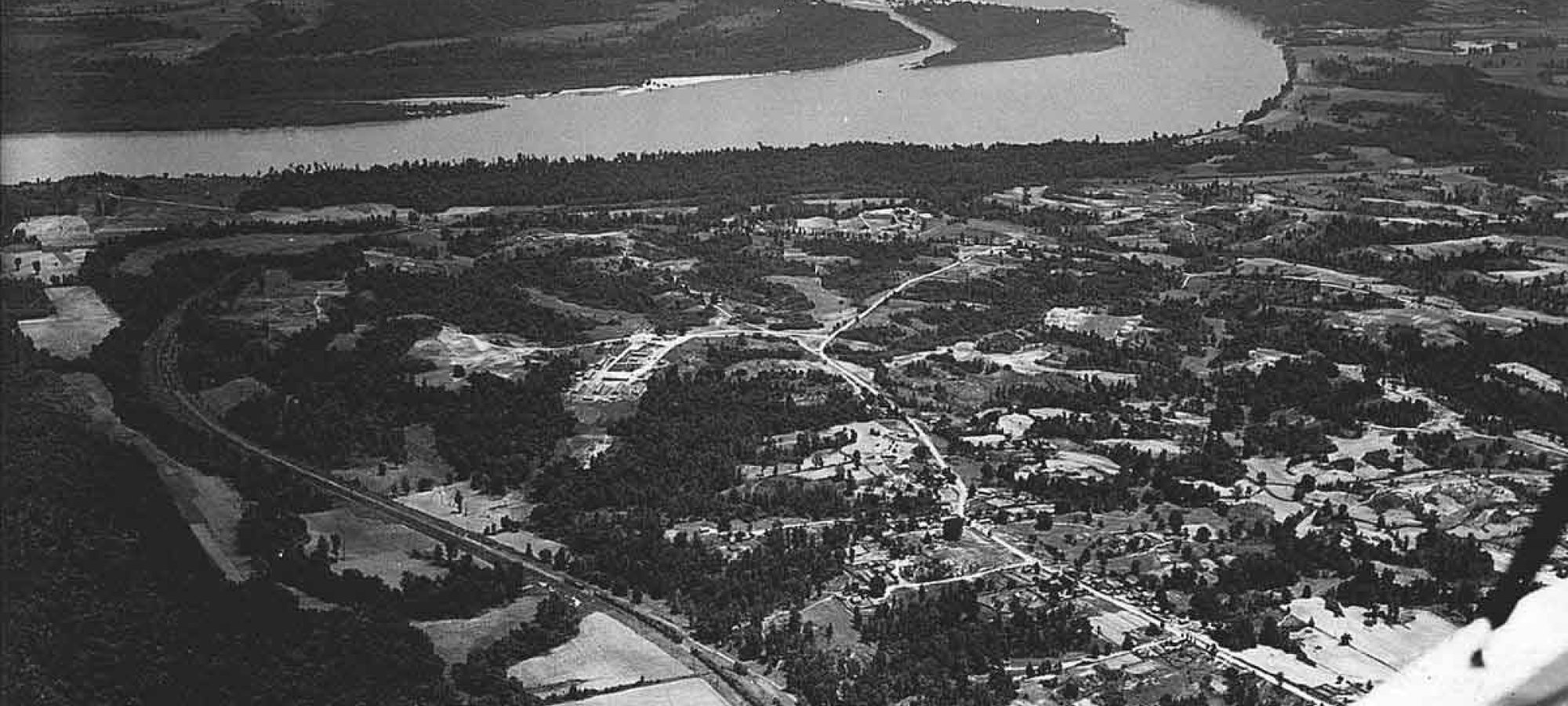 Aerial view of a winding river with surrounding landscape in grayscale.