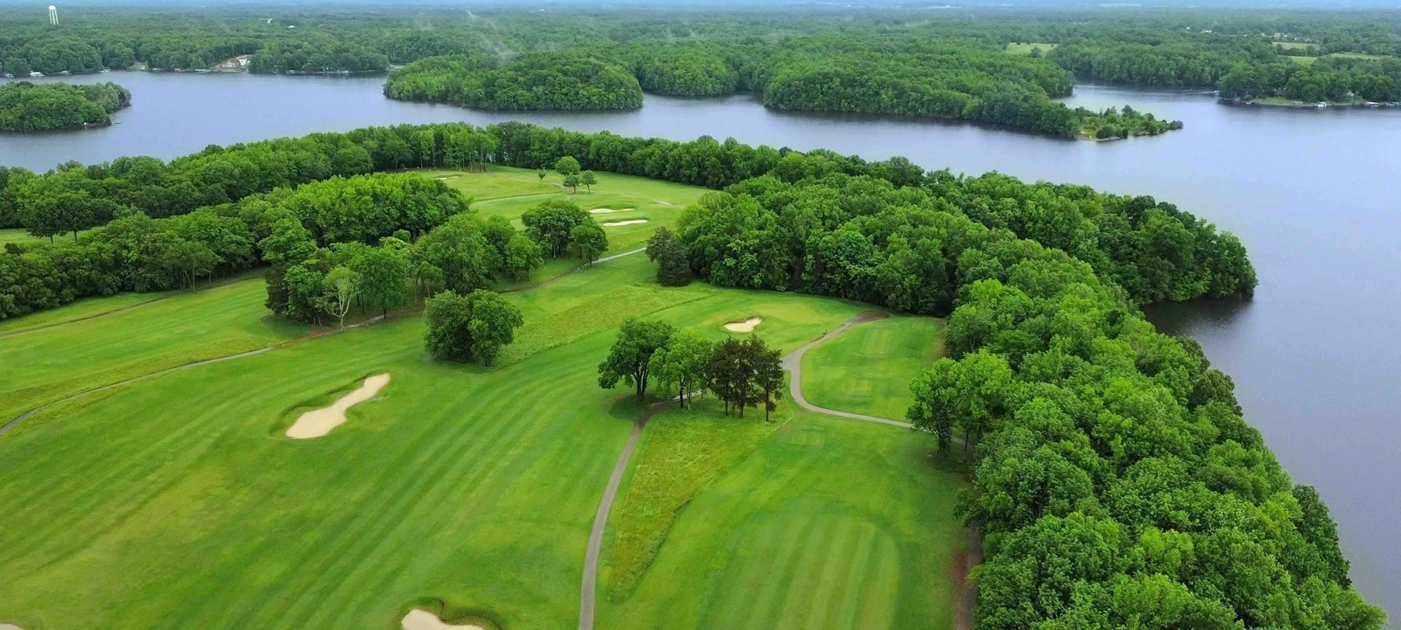 A lush green golf course on a peninsula surrounded by blue lake water