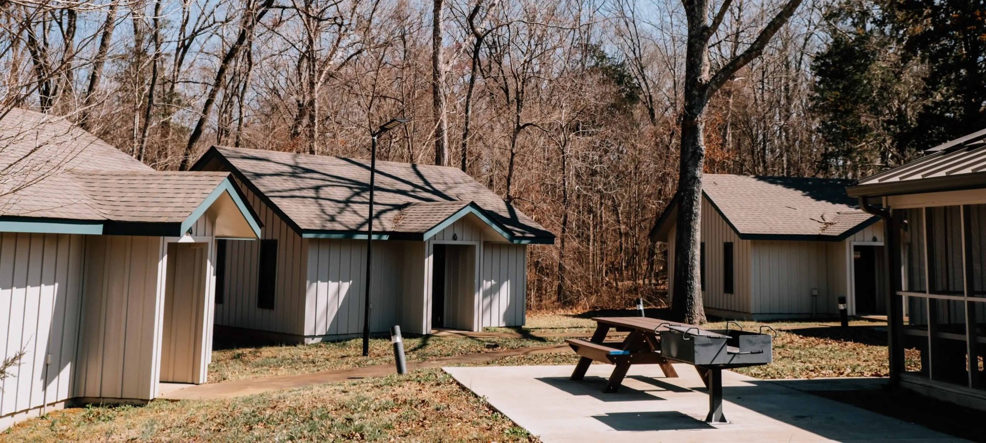 Row of small cabins with a picnic table in a wooded area.