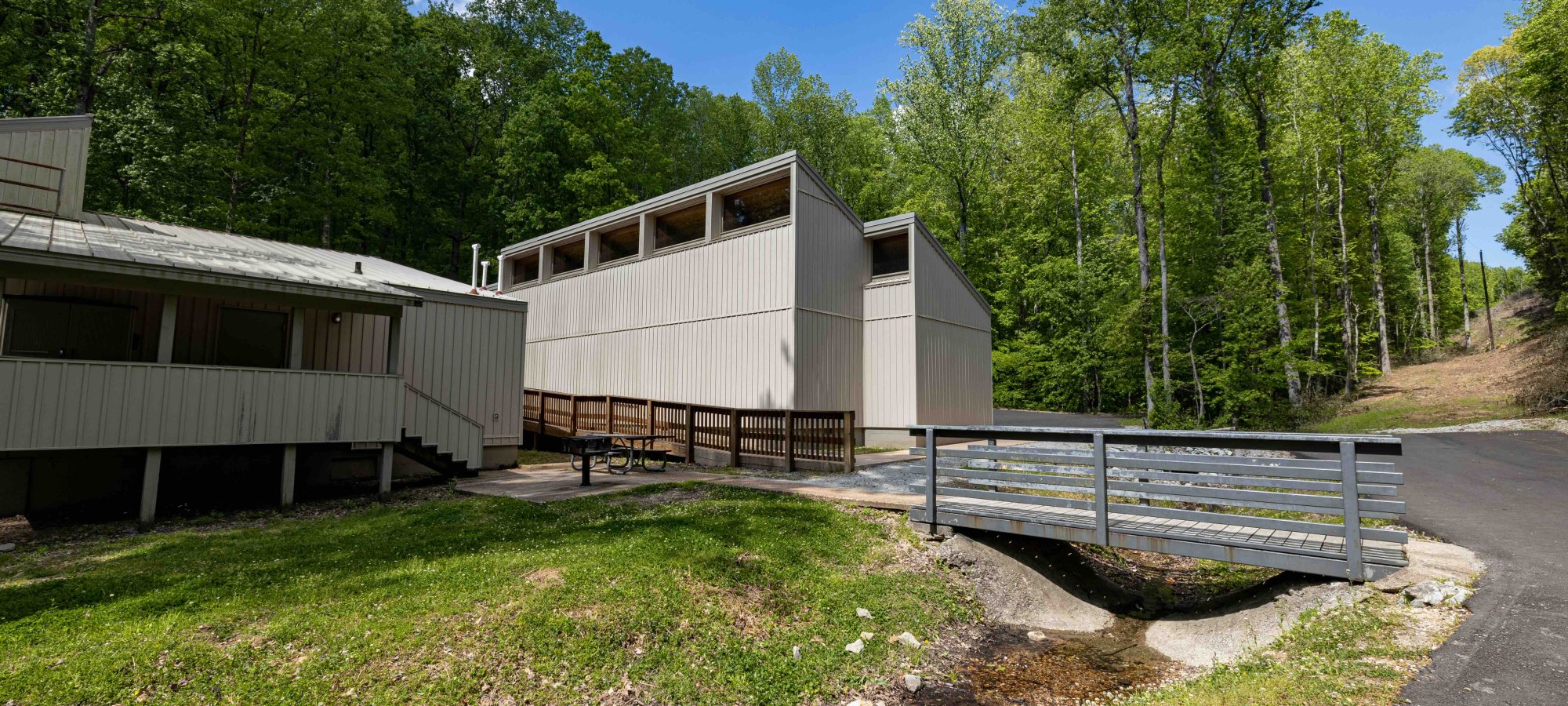 Modern building with bridge access surrounded by lush greenery.