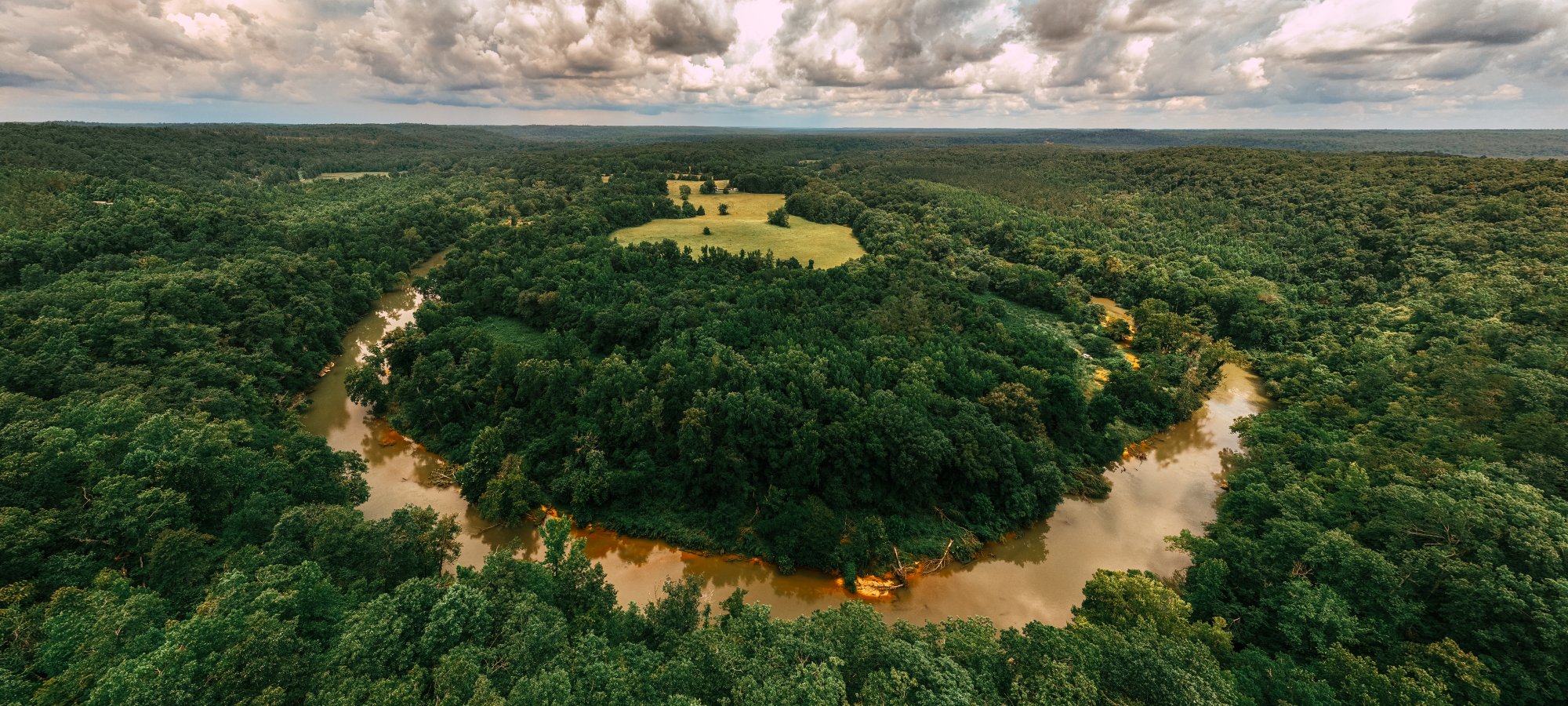 Aerial view of a winding river through a dense green forest.