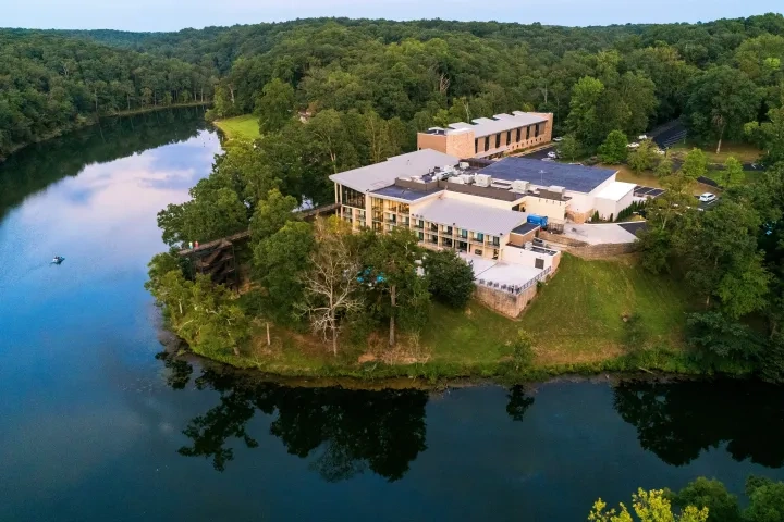 Aerial view of a riverside building surrounded by lush green forest.