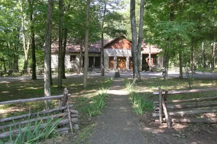 Cabin tucked back in the trees with a gravel walkway.