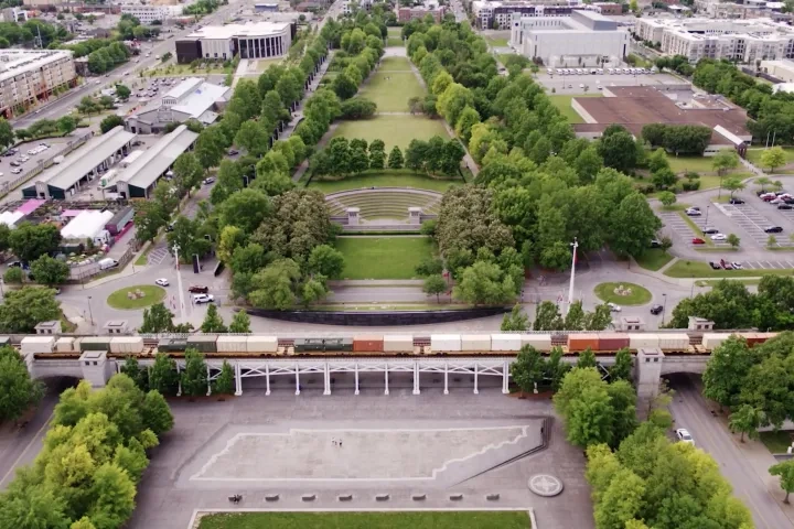 Aerial view of a city park with train tracks and surrounding buildings.