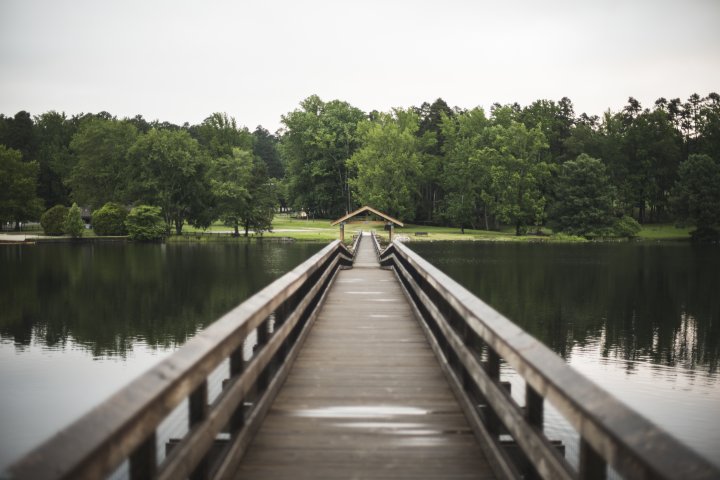 wooden bridge extending across a lake with guard rails.