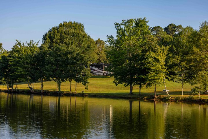 view of lake and across the water is land with some trees and an RV parked