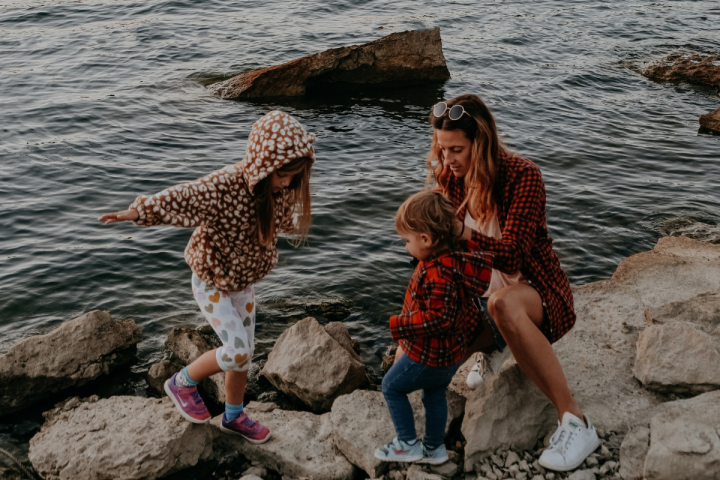 A family sits on rocks next to a lake during the fall.