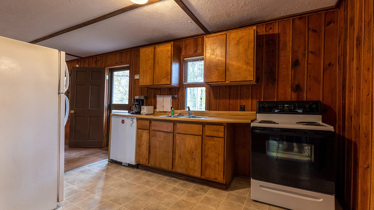 A wall of cabinets inside a cabin's kitchen, with a dishwasher and a overn 