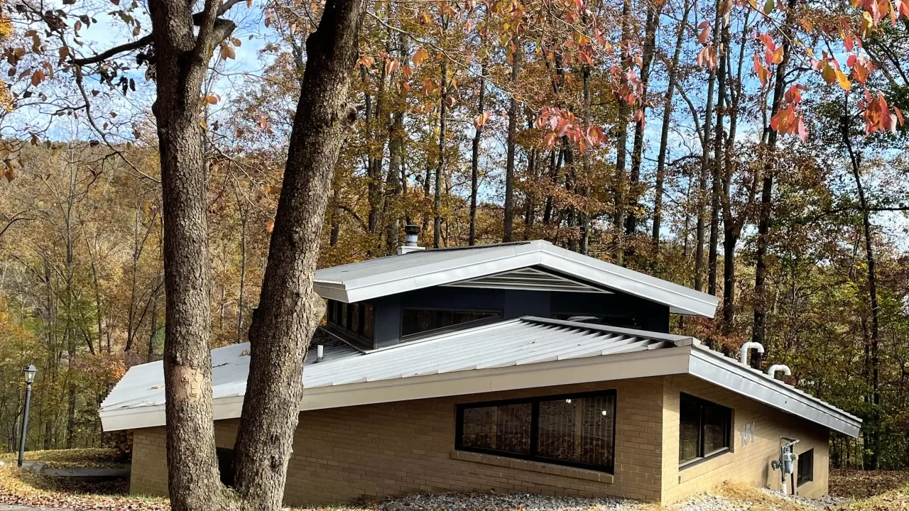 Modern house in autumn woods, surrounded by red and orange leaves.