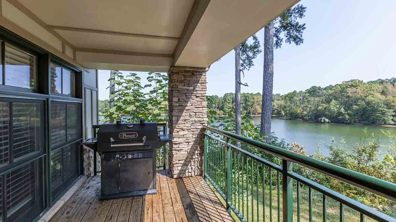 Balcony overlooking a lake with a barbecue grill.