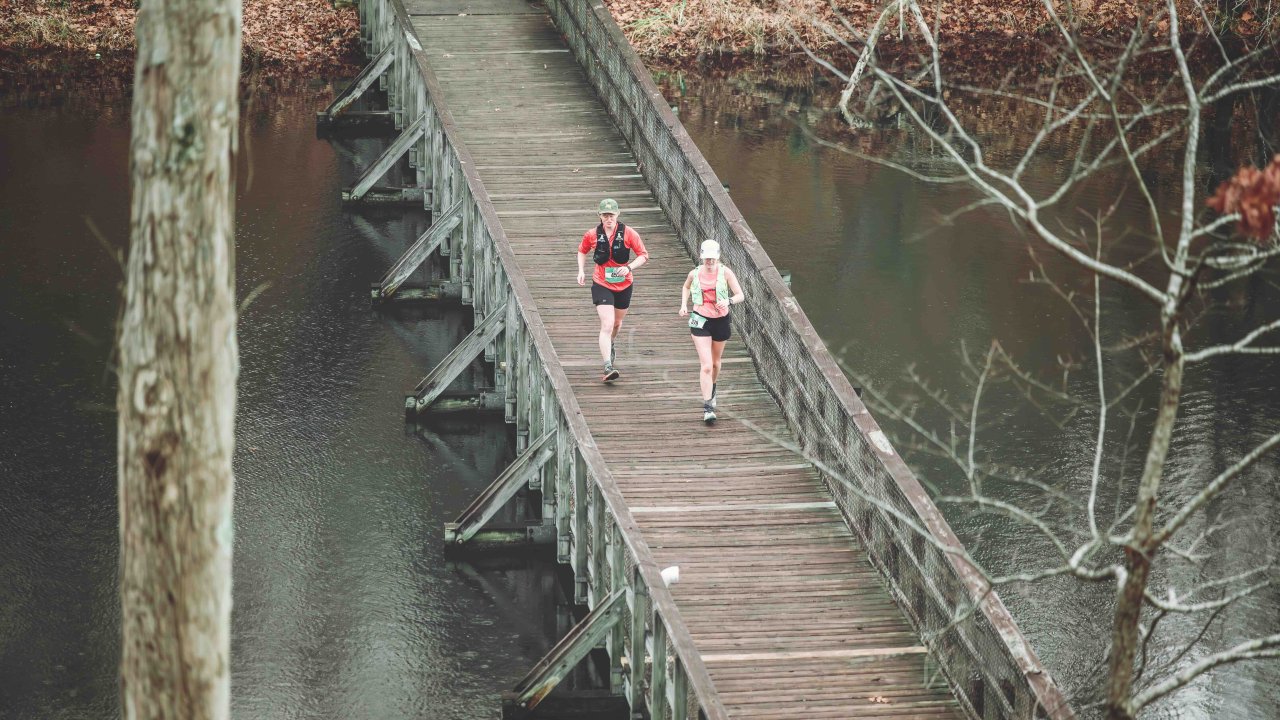 two people jogging across a wooden bridge