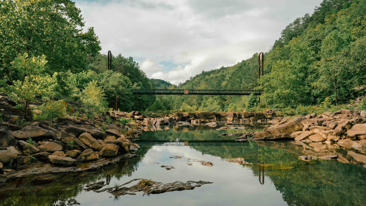 view of river with rocks near the edges and a bridge in the distance