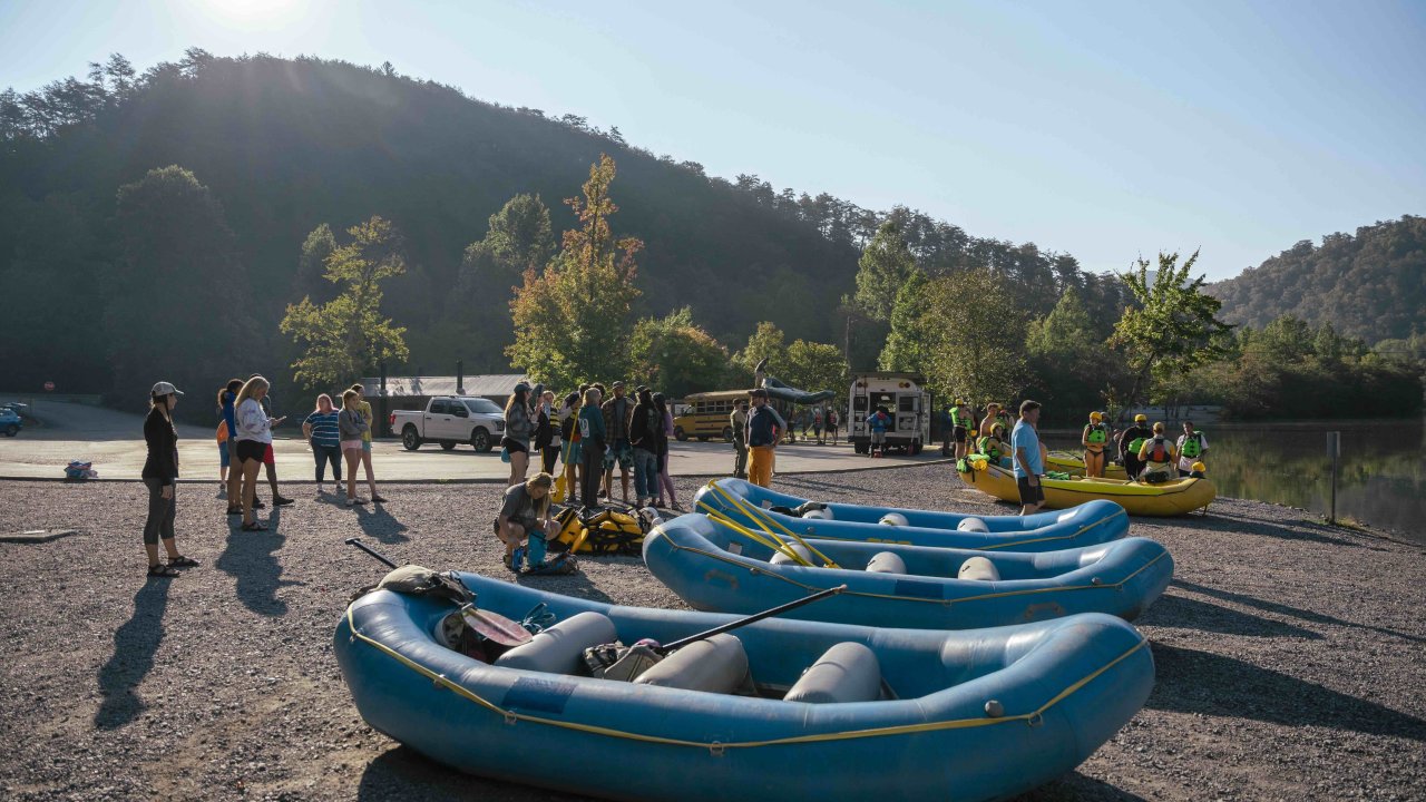 several rafts on the ground with people in groups behind them or people getting ready to get in the water