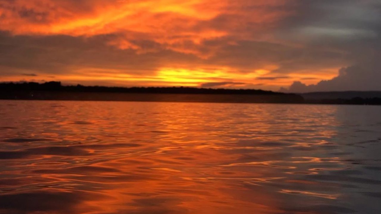 Sunset over a lake with vibrant orange and red colors reflecting on water.