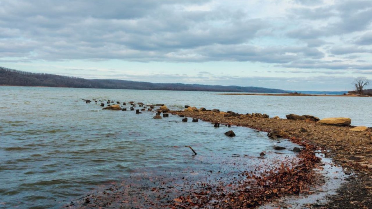 Cloudy sky over a serene lake with a rocky shoreline.