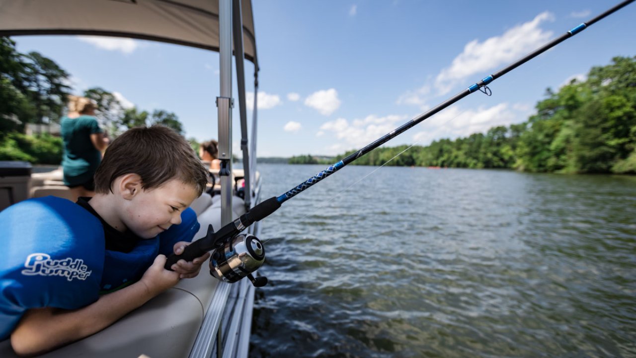 Young boy fishing from a boat on a sunny day.