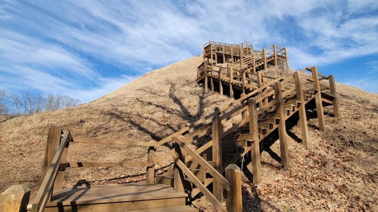 Wooden staircase leading up a barren hill under a blue sky with wispy clouds.