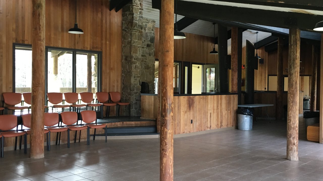 Interior view of a spacious cabin with wooden walls and stone pillars.