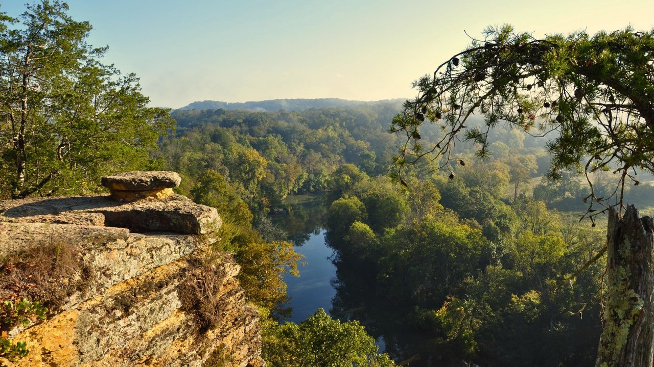 Scenic view of a river flowing through a forest from a high cliff at sunrise.