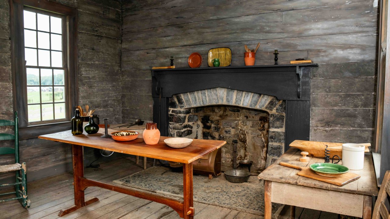Rustic wooden kitchen with a large fireplace and vintage utensils.
