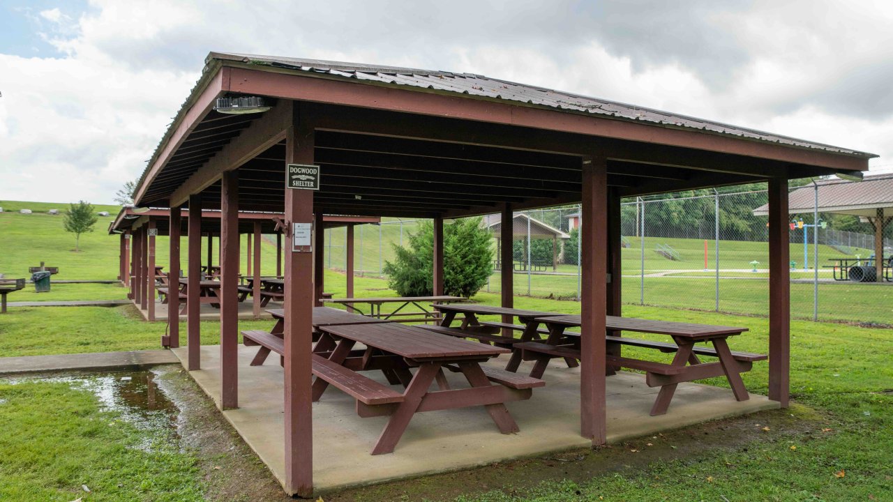 a row of shelters that offer picnic tables and have a concrete path leading to them.