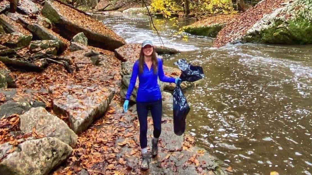 woman with trash bag near a river cleaning