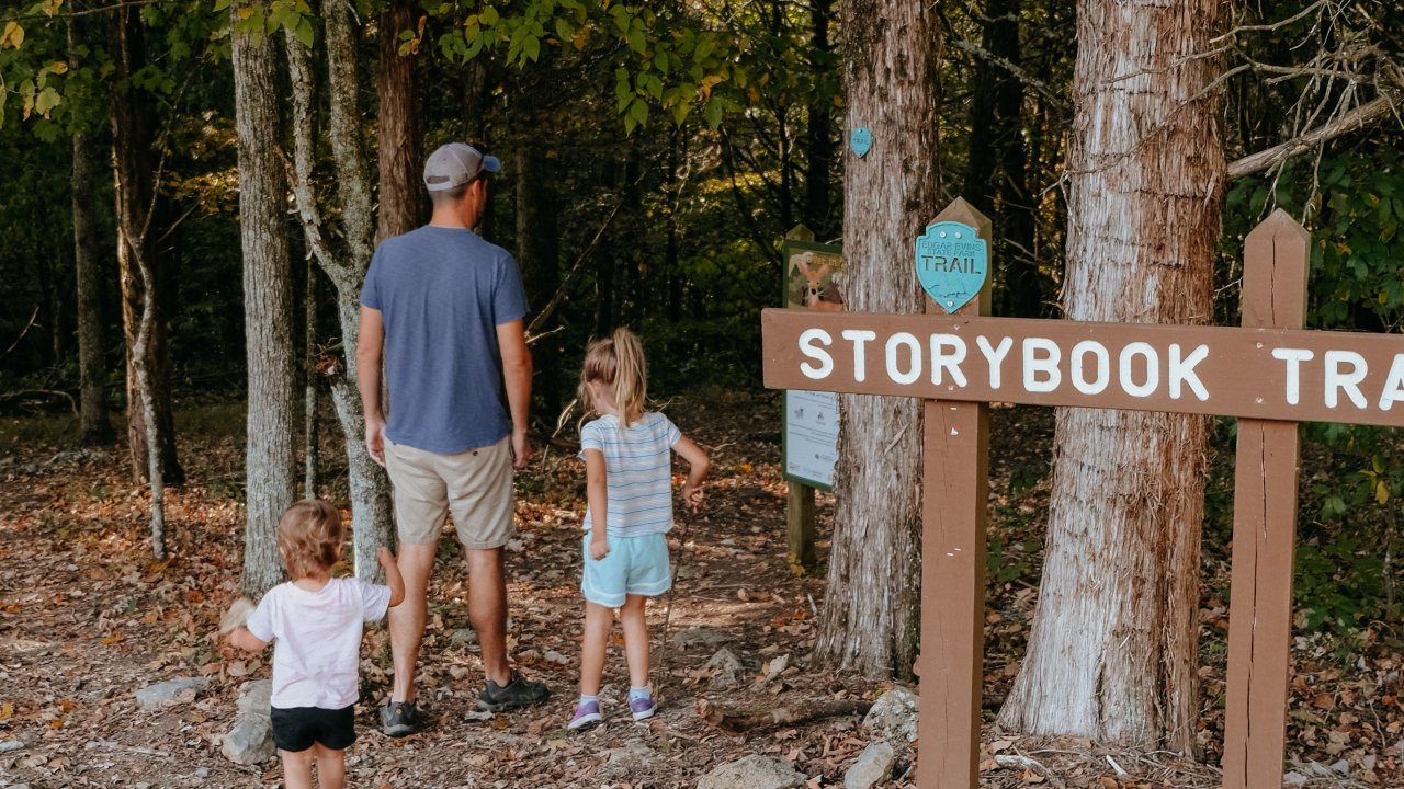 Family of four walking on Storybook Trail in a forest.