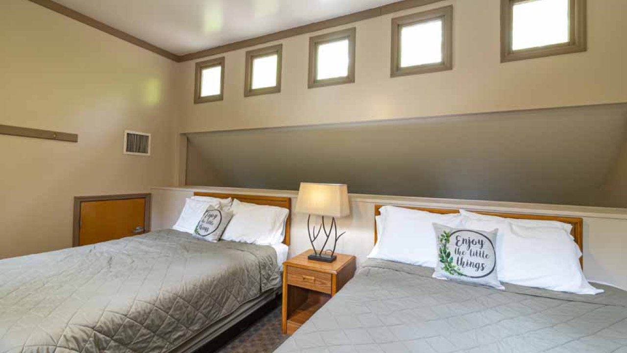 Modern bedroom with two beds, side lamp, and skylight windows.