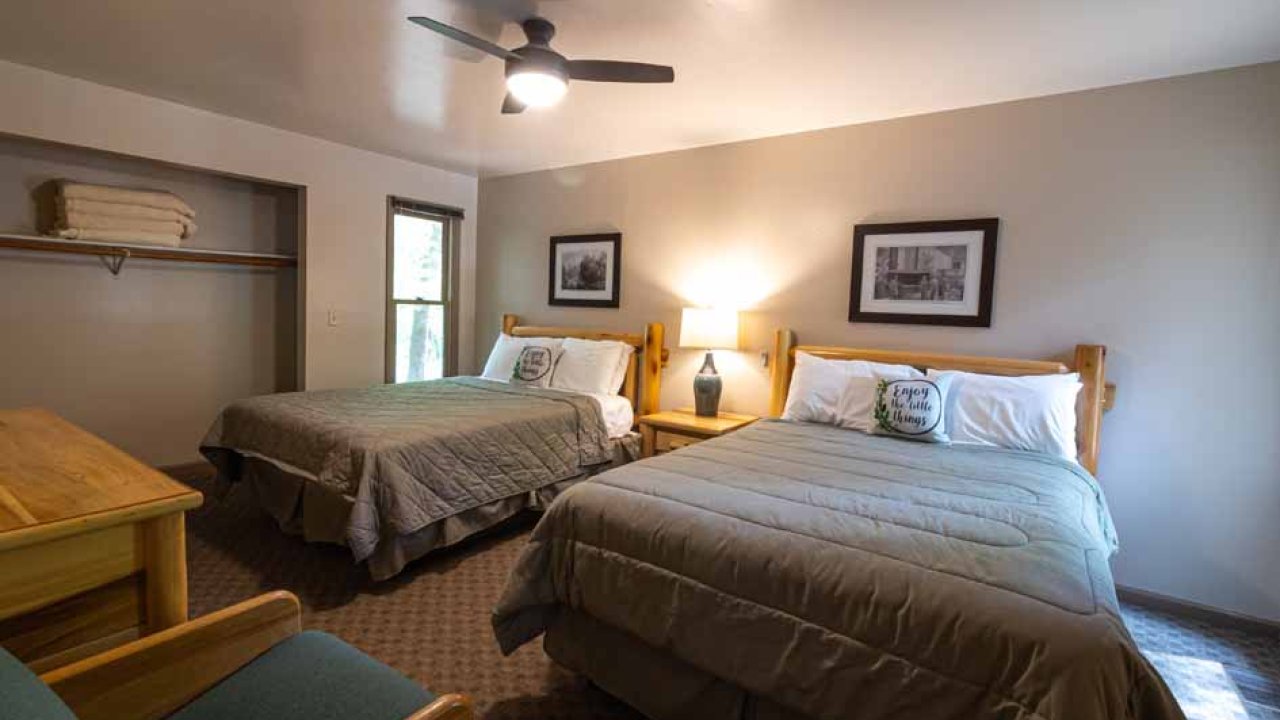Cozy, well-lit bedroom with two twin beds, green armchair, and ceiling fan.