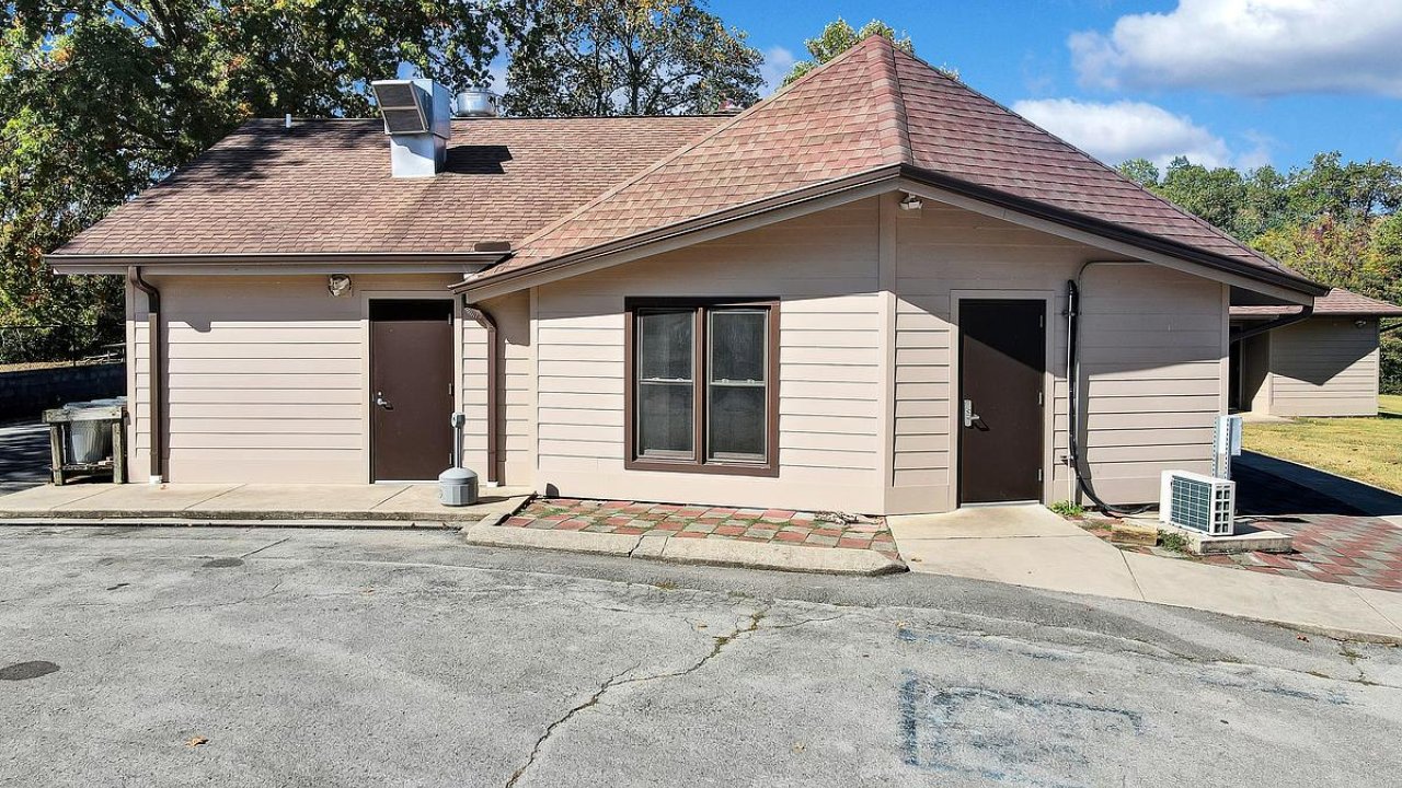 Tan single-story house with cracked driveway and bare trees.