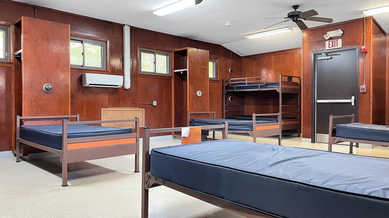 Dormitory room with multiple beds and wooden walls.