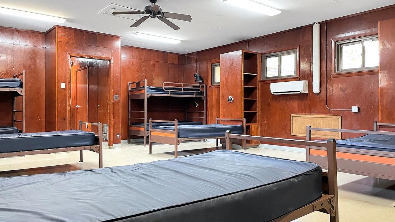 Spacious dormitory room with multiple beds and wooden furnishings.